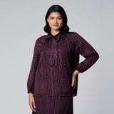 Plus size model wearing MS. READ deep plum and black tie-neck blouse with subtle shimmer stripes and elasticated long sleeves.